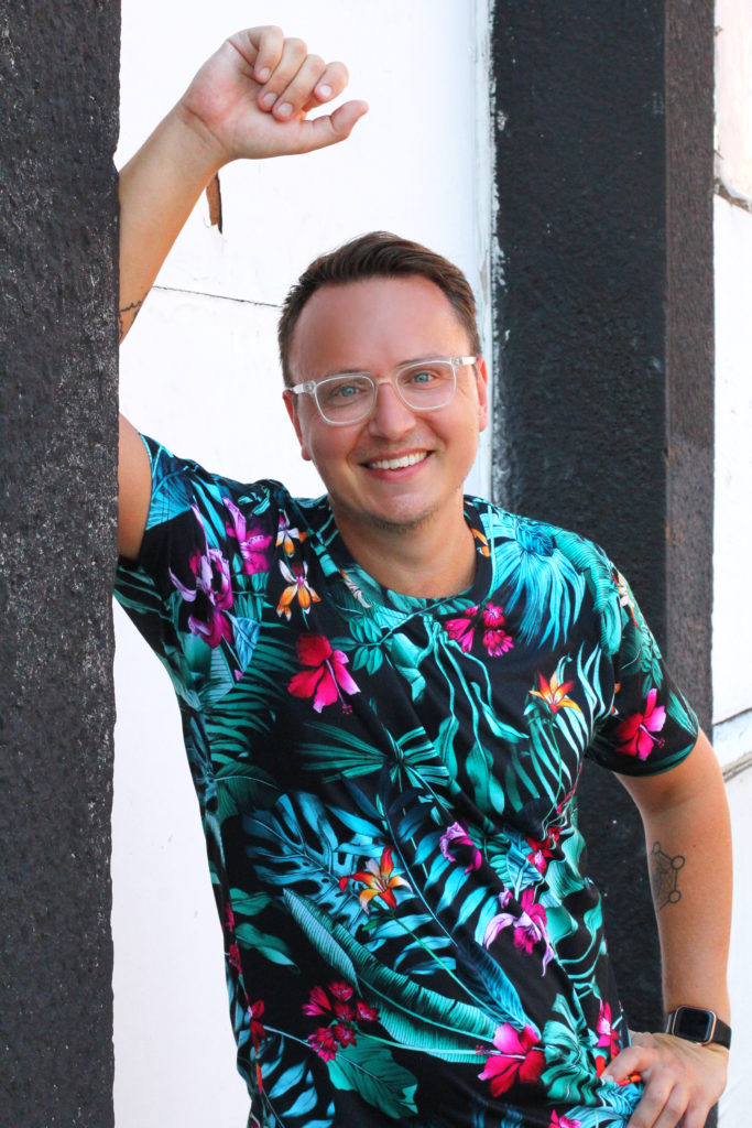 Liam Carnahan of Inkwell Content smiling at the camera in a colorful shirt while leaning against a wall
